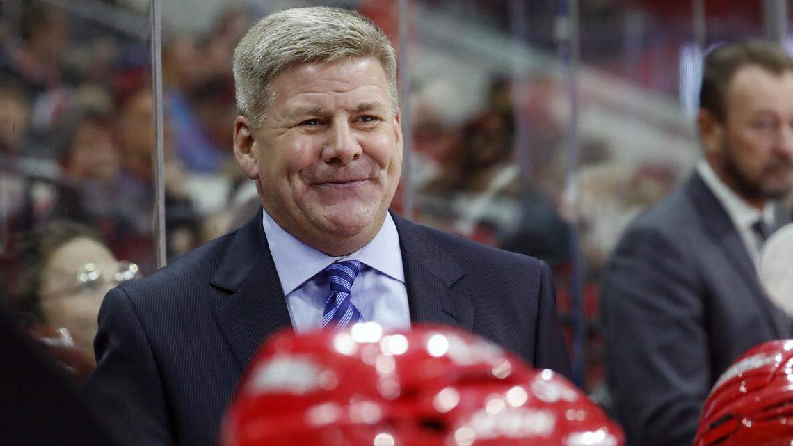 The Canes' head coach Bill Peters enjoys a laugh during a game against the Tampa Bay Lightning .