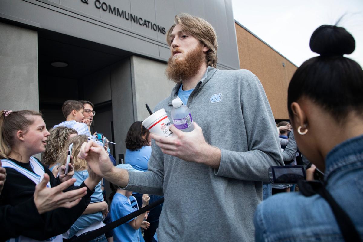 Brady Manek high-fives fans outside the Dean Dome in Chapel Hill, N.C. with his teammates as the UNC basketball team begins their journey to the Final Four in New Orleans on Wednesday, March 30, 2022.