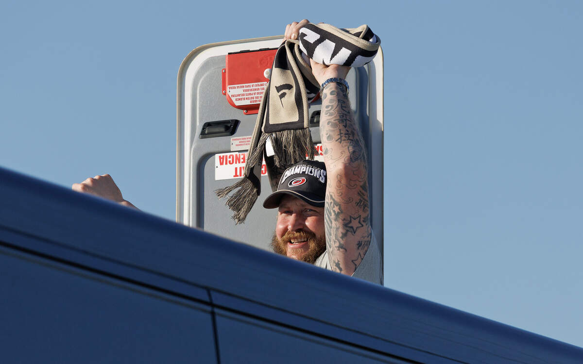 Carolina Hurricanes forward Nicolas Deslauriers leans out of a bus to greet fans as the team departs Raleigh-Durham International Airport on Monday, June 15, 2026, after defeating the Vegas Golden Knights to win the Stanley Cup.