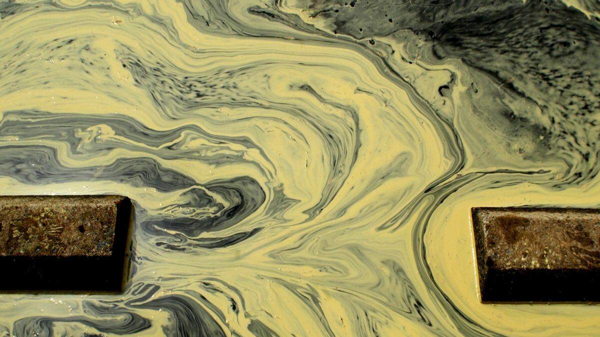 An image of tree pollen swirling in a parking lot after a rain shower.