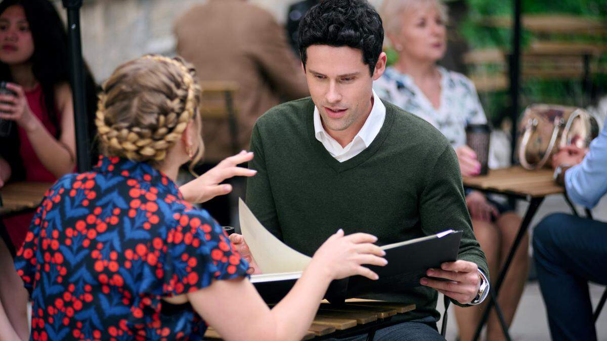 Jaicy Elliot and Benjamin Hollingsworth look at fashion sketches in the Hallmark movie “Romance in Style.”