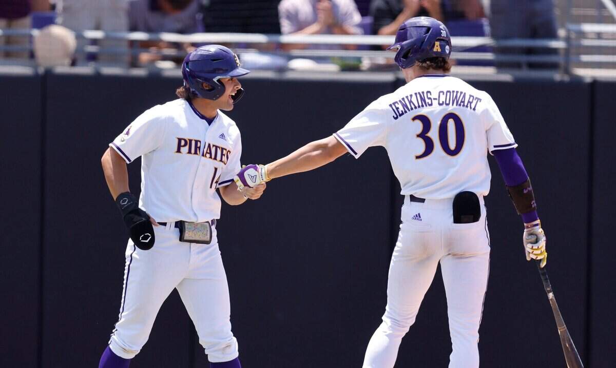 East Carolina’s Zach Agnos (14) talks with Jacob Jenkins-Cowart (30) after Agnos scored on a passed ball in the first inning during ECUs game against Texas in the Greenville Super Regional at Clark-LeClair Stadium Friday, June 10, 2022.