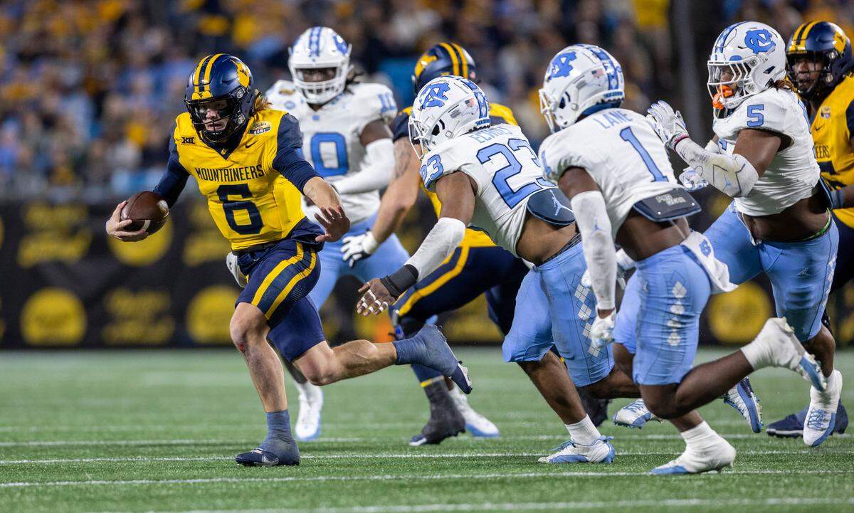 West Virginia quarterback Garrett Greene (6) carries the ball ahead of the North Carolina defense in the fourth quarter during the Duke’s Mayo Bowl on Wednesday, December 27, 2023 at Bank of American Stadium in Charlotte, N.C. Greene used for 75 yards in the Mountaineers’ victory.