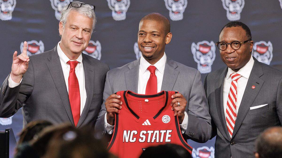 New N.C. State men’s basketball head coach Justin Gainey, center, poses for a photograph with Athletic Director Boo Corrigan and Chancellor Kevin Howell during a press conference at Lenovo Center on April 1.