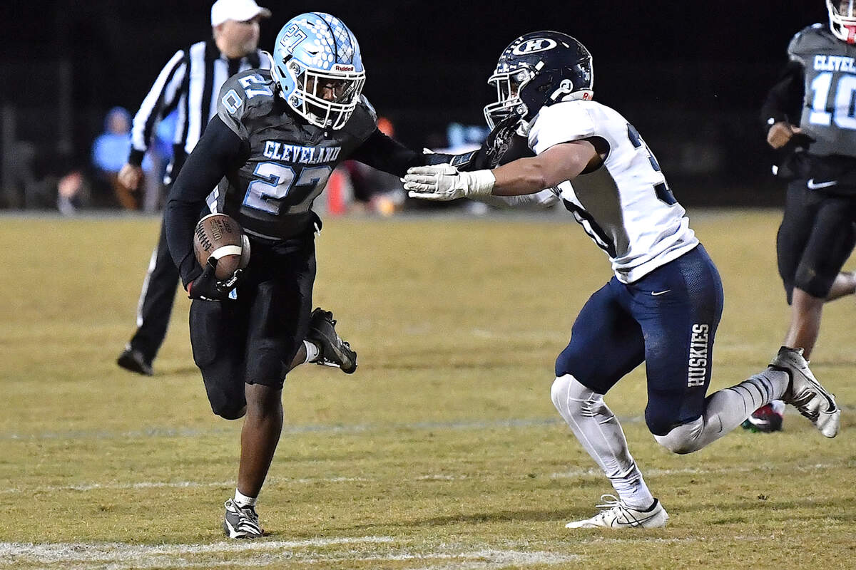 Cleveland running back Kaleb Ferrell (27) runs for yardage and stiff-arms Heritage’s Seth Rucker (30) during the second half. The Cleveland Rams and the Heritage Huskies met in the first round of the NCHSAA 4A playoffs in Clayton, N.C. on November 15, 2024.