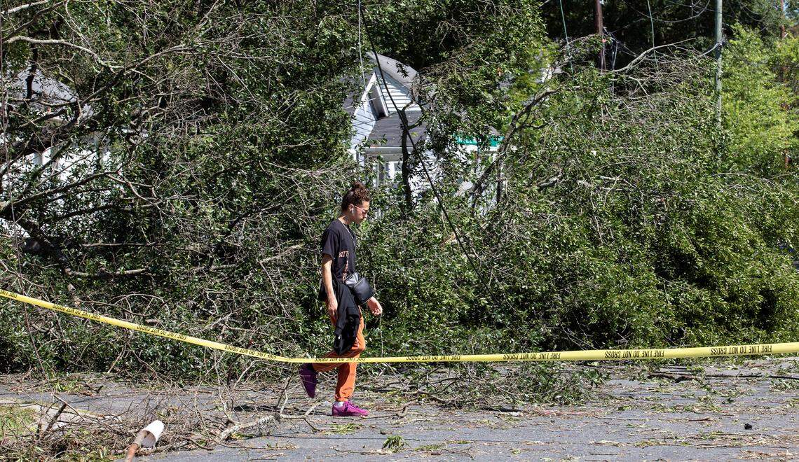 A person walks by a downed tree near the intersection of Englewood Avenue and Clarendon Street on Wednesday, Aug. 16, 2023, following strong storms in Durham, N.C. Tuesday evening.
