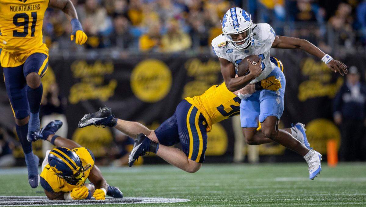 West Virginia’s Caden Biser (36) stops North Carolina quarterback Conner Harrell (15) for a loss of two yards in the first quarter during the Duke’s Mayo Bowl on Wednesday, December 27, 2023 at Bank of American Stadium in Charlotte, N.C.