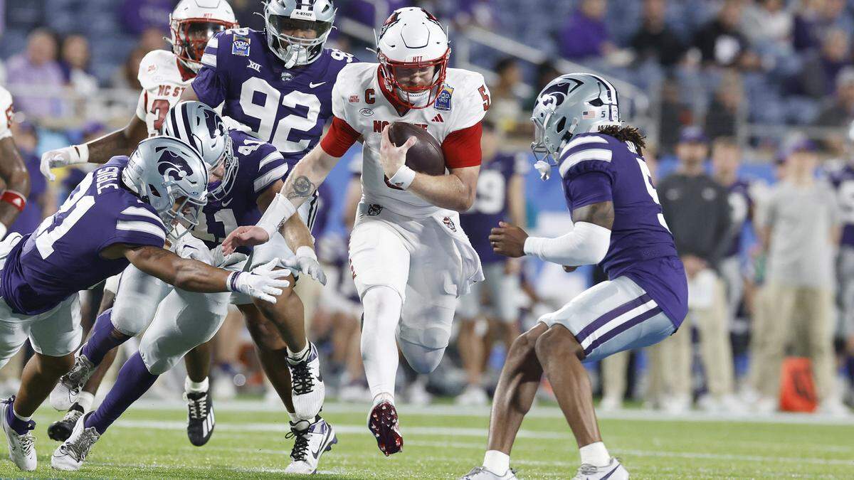 N.C. State quarterback Brennan Armstrong (5) gains yards while pursued by Kansas State defenders during the first half of N.C. State’s game against Kansas State in the Pop-Tarts Bowl at Camping World Stadium in Orlando, Fla., Thursday, Dec. 28, 2023.