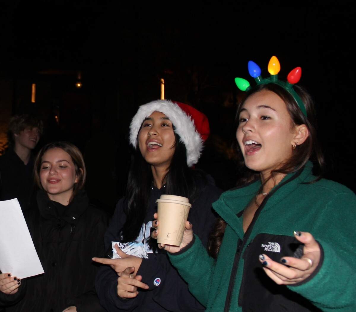 Enloe High School students (from left to right) Sofia Pellegrino, Jiya Shu Bhure and Penny Choy sing Christmas carols on Williamsborough Court in Raleigh, N.C. on Dec. 11, 2023 to raise money for the 2023 Enloe Charity Ball.