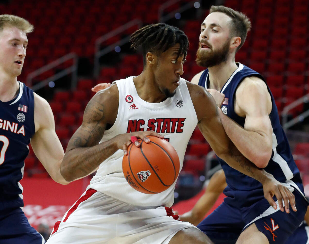 N.C. State’s Manny Bates (15) drives as Virginia’s Jay Huff (30) defends during the second half of Virginia’s 64-57 victory over N.C. State at PNC Arena in Raleigh, N.C., Wednesday, February 3, 2021.