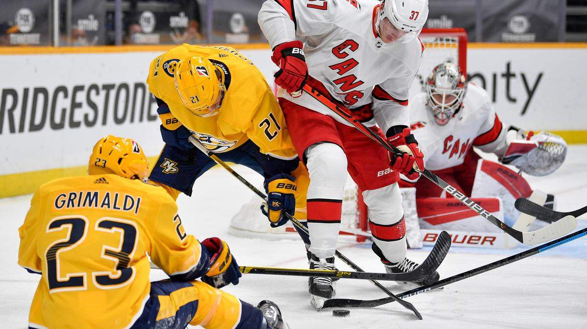 Nashville Predators center Nick Cousins (21) and right-wing Rocco Grimaldi (23) fight for the puck with Carolina Hurricanes right wing Andrei Svechnikov (37) during the first period of an NHL hockey game in Nashville, Tenn., Monday, Jan. 18, 2021. (Andrew Nelles/The Tennessean via AP)