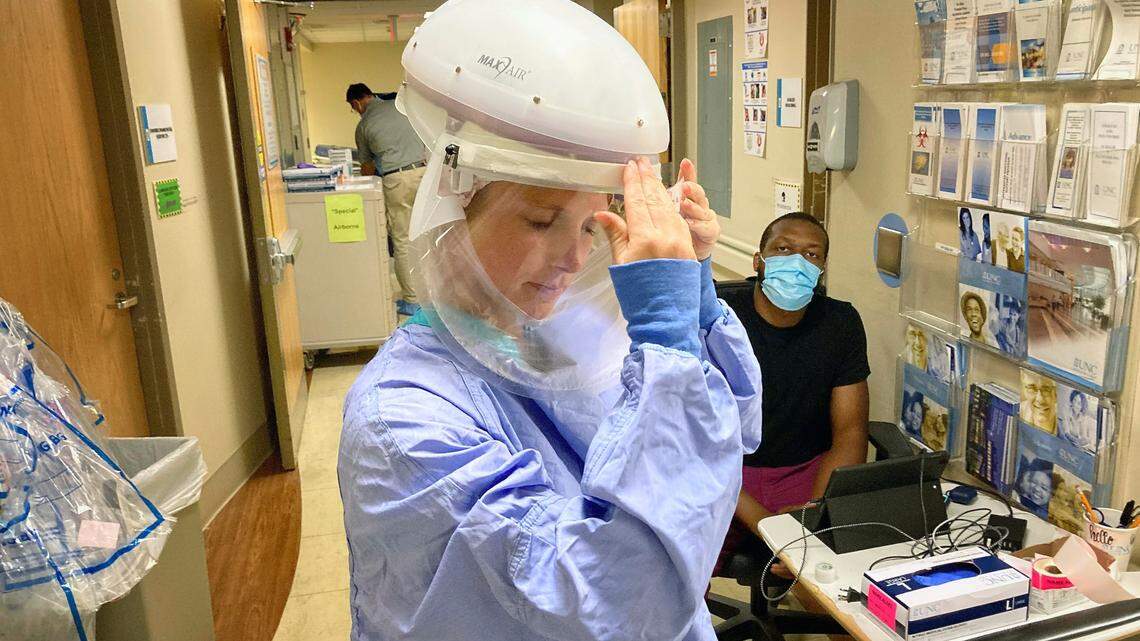 Alix Theodossiou, RN, adjusts the face shield on her negative pressure helmet before entering the COVID-19 patient care areas of the Medical ICU unit at UNC Hospital Monday, July 13, 2020.