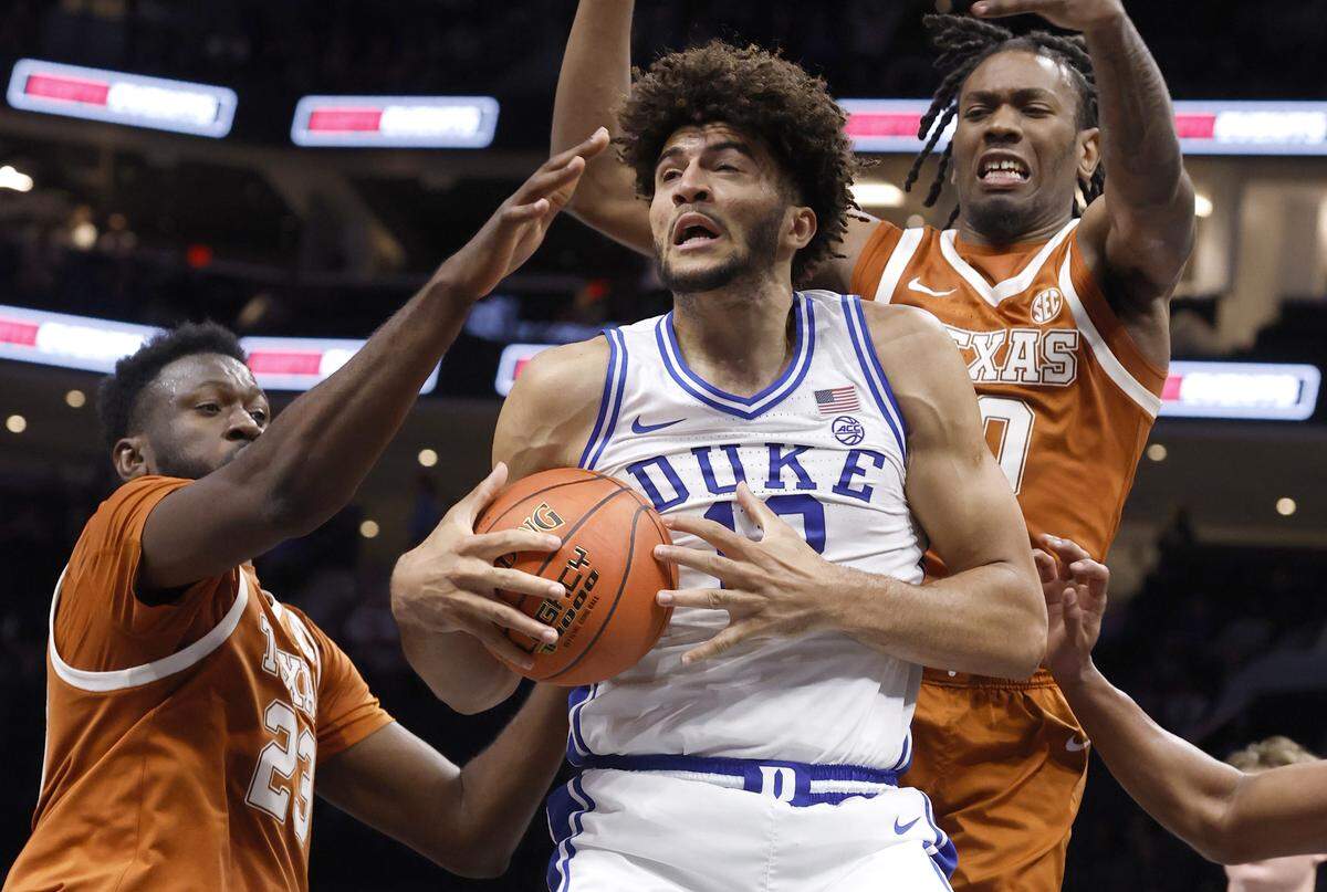 Duke’s Cameron Boozer (12) pulls in an offensive rebound from Texas’ Nic Codie (10) and Lassina Traore (23) during the second half of Duke’s 75-60 victory over Texas in the Dick Vitale Invitational at the Spectrum Center in Charlotte, N.C., Tuesday, Nov. 4, 2025.