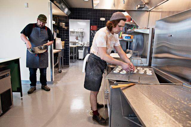 Baker Joshua Bellamy, right, preps donuts to fry as John Knox makes a chocolate glaze on Friday, March 18, 2022, at the new Raleigh bakery, Bright Spot Donuts, which will open soon near the Five Points Neighborhood.