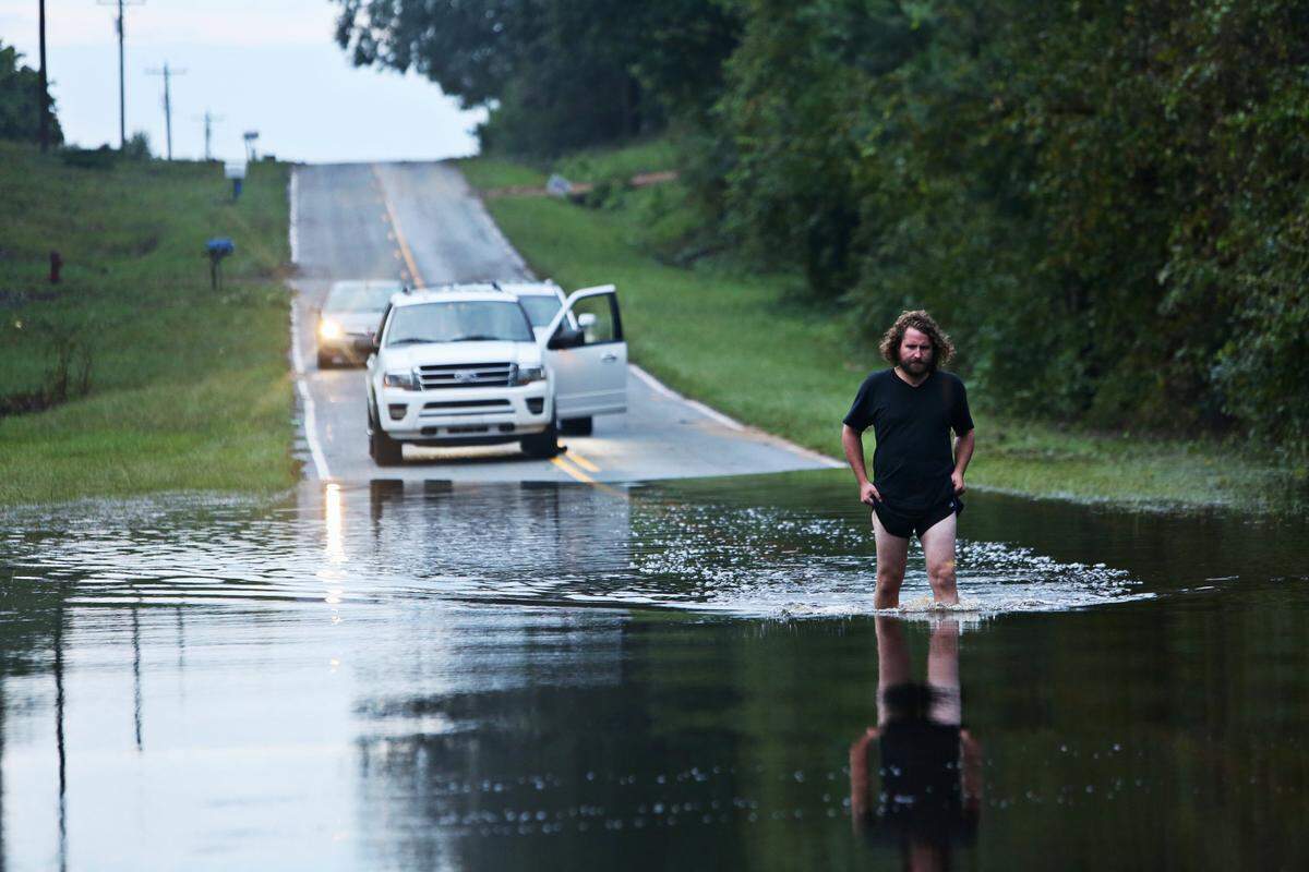 Jack Goodwin, a journalist who came down from New York, checks the depth of the water before the crew crosses over a flooded street in Goldsboro on Sunday, Sept. 16, 2018.