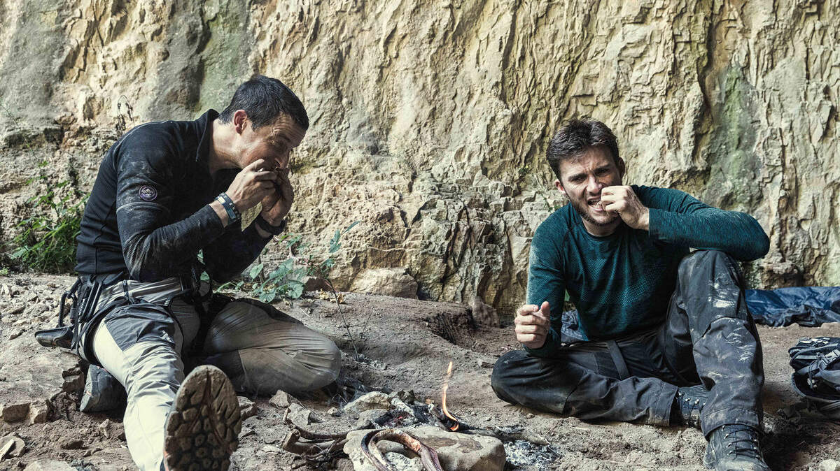 Bear Grylls, left, and Scott Eastwood eat snakes on "Running Wild with Bear Grylls" on NBC.