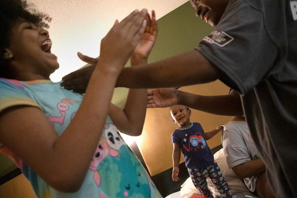 One-year-old Sahkahanii McCullers smiles as Jayde Edwards, 10, and London Jones, 13, share a laugh in an extended-stay hotel room on Monday, July 25, 2022, in Raleigh, N.C.