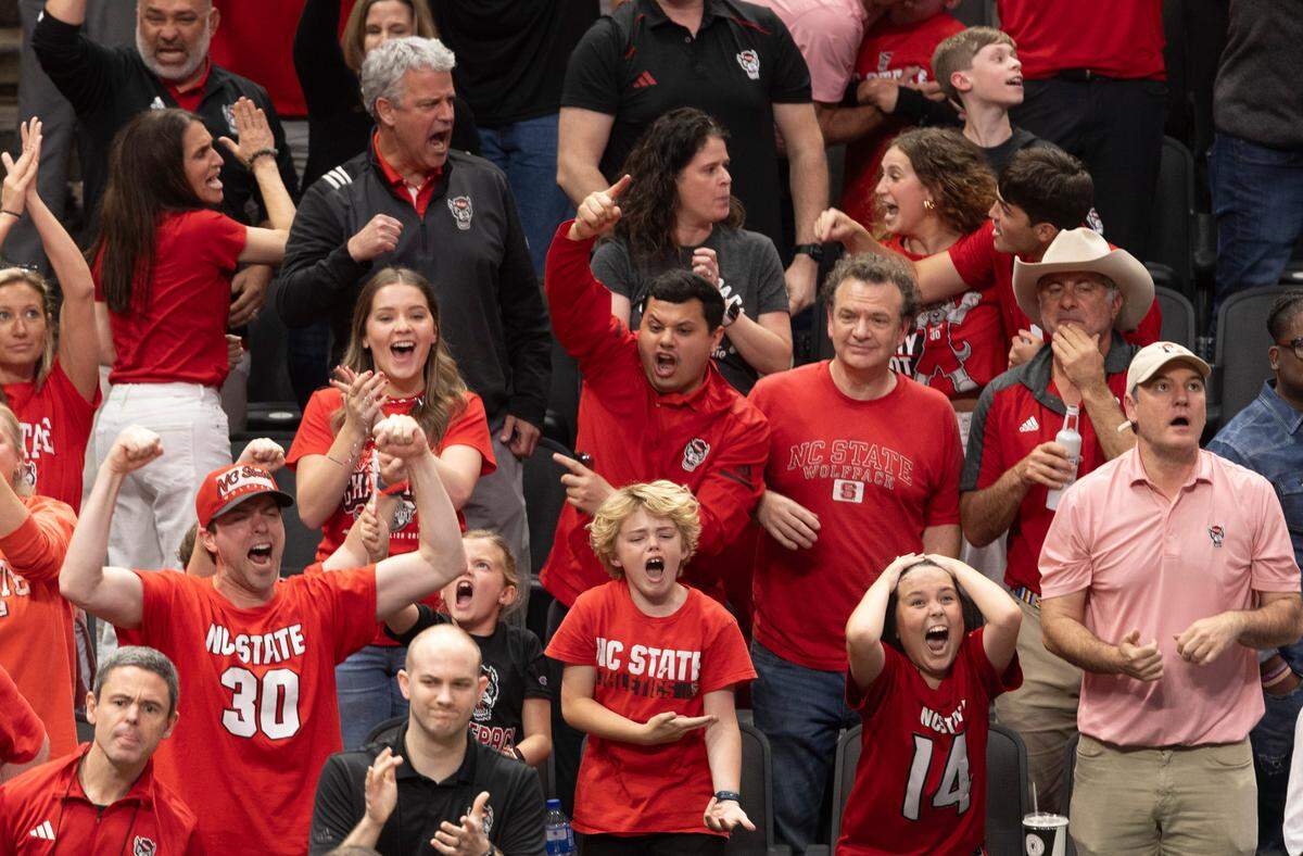 Wolfpack fans behind the N.C. State bench celebrate as they take a second half lead over Duke during the NCAA South Regional final on Sunday, March 31, 2024 at the American Airlines Center in Dallas, Texas.