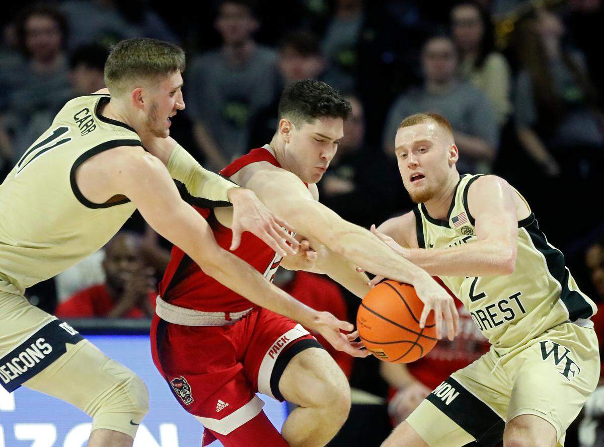 N.C. State’s Michael O’Connell battles Wake Forest’s Andrew Carr and Cameron Hildreth for a loose ball during the first half of the Wolfpack’s game on Saturday, Feb. 10, 2024, at Lawrence Joel Veterans Memorial Coliseum in Winston-Salem, N.C.