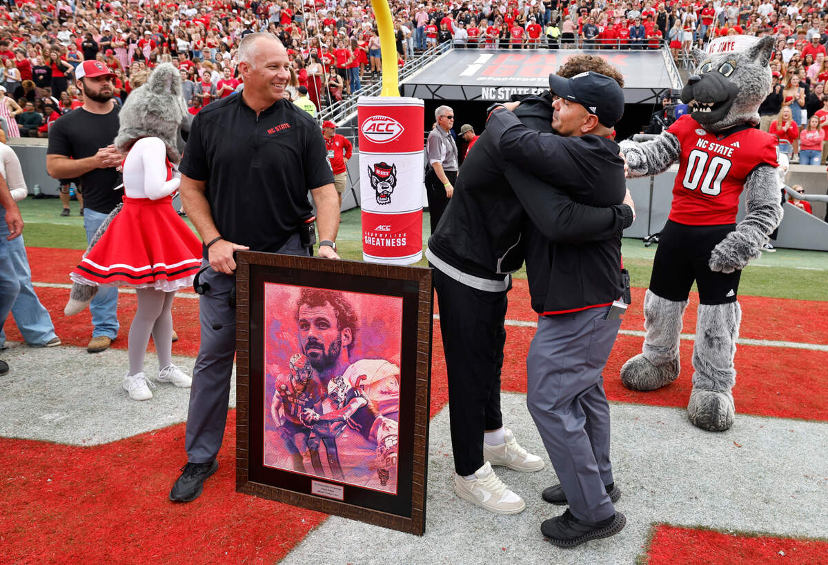 Former N.C. State linebacker Payton Wilson gets a hug from defensive coordinator Tony Gibson after Wilson was inducted in the Ring of Honor during the Wolfpack’s game against Stanford at Carter-Finley Stadium in Raleigh, N.C., Saturday, Nov. 2, 2024. N.C. State head coach Dave Doeren looks on.