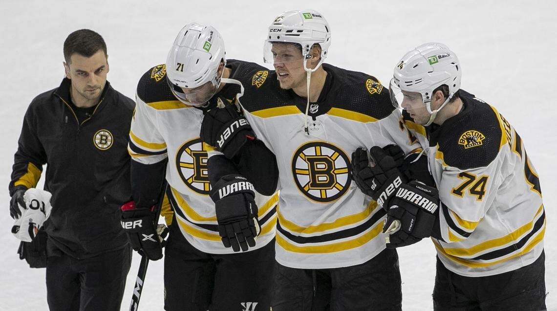Boston Bruins Taylor Hall (71) and Jake DeBrusk (74) escort teammate Hampus Lindholm (27) off the ice after an injury in the second period against the Carolina Hurricanes on Wednesday, May 4, 2022 during game two of their Stanley Cup first round series at PNC Arena in Raleigh, N.C.