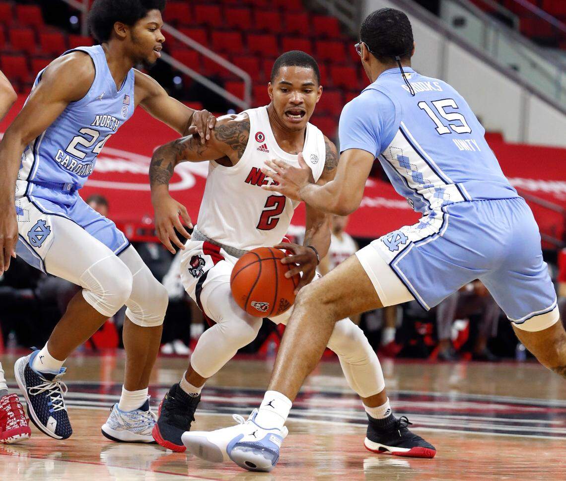 N.C. State’s Shakeel Moore (2) drives between North Carolina’s Kerwin Walton (24), left and Garrison Brooks (15) during the first half of N.C. State’s game against UNC at PNC Arena in Raleigh, N.C., Tuesday, December 22, 2020.