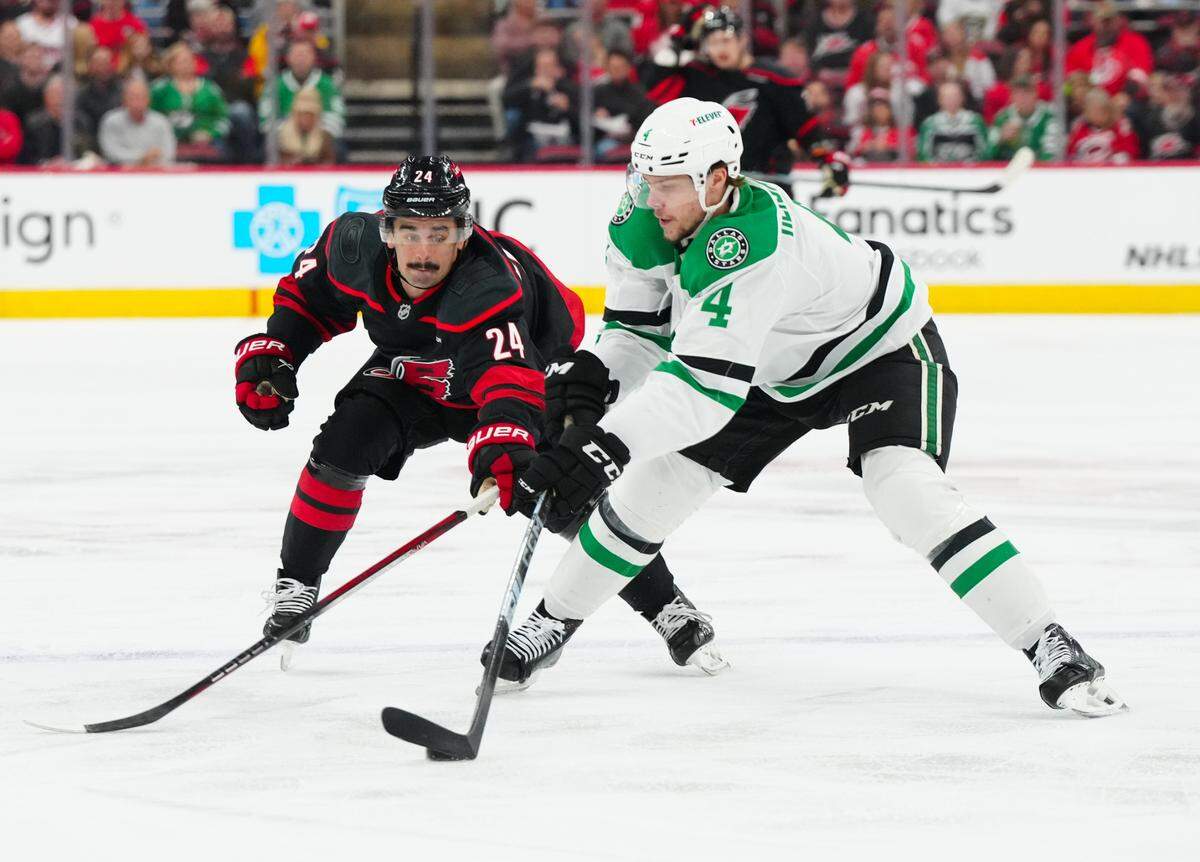 Nov 25, 2024; Raleigh, North Carolina, USA; Carolina Hurricanes center Seth Jarvis (24) reaches for the puck against Dallas Stars defenseman Miro Heiskanen (4) during the first period at Lenovo Center. Mandatory Credit: James Guillory-Imagn Images