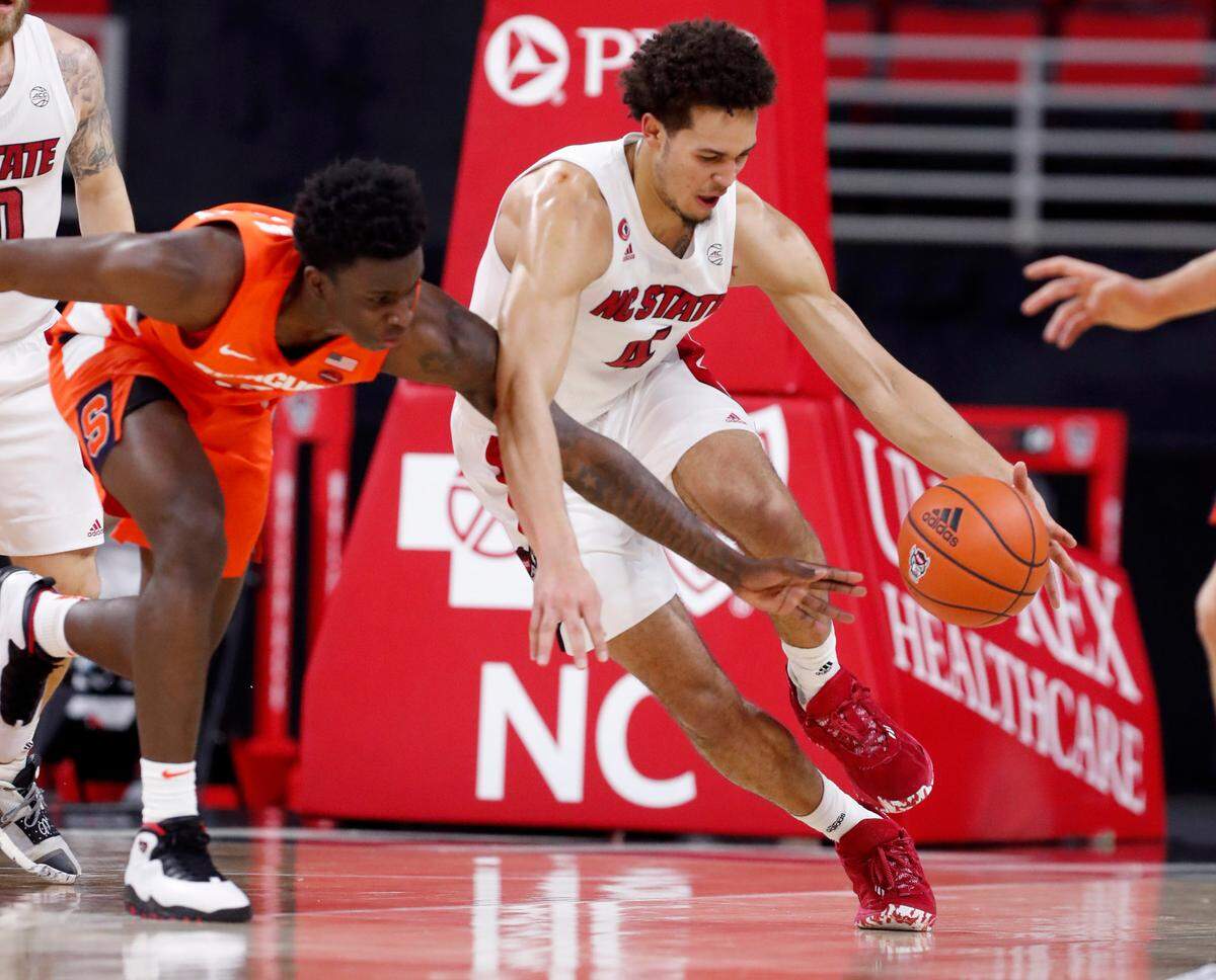 N.C. State’s Jericole Hellems (4) brings the ball past Syracuse’s Kadary Richmond (3) during the first half of N.C. State’s game against Syracuse at PNC Arena in Raleigh, N.C., Tuesday, February 9, 2021.