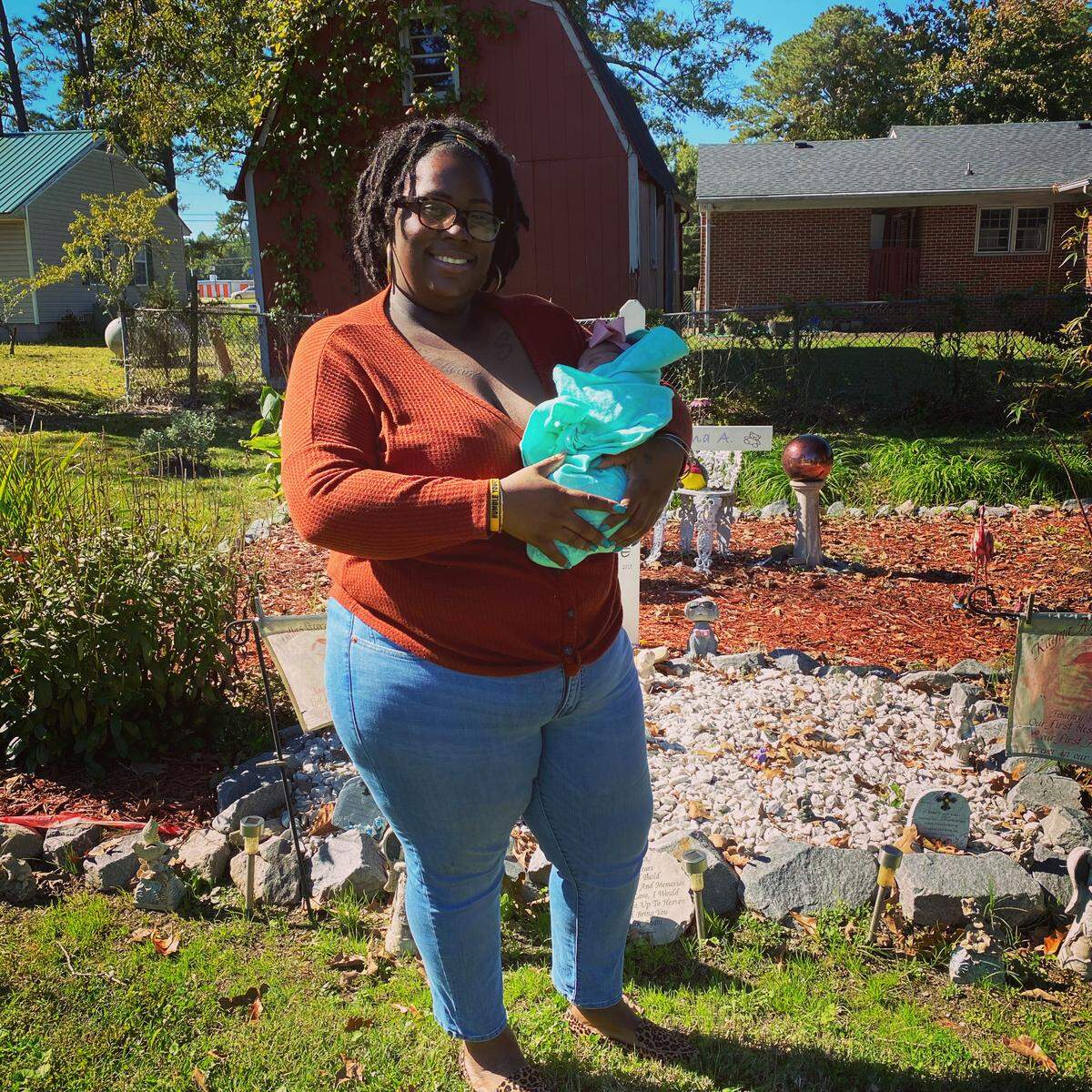 Renee Schoolfield stands with her infant daughter born in September 2020, Azlyn Briel, in front of the burial site for her two children who died after being born prematurely.