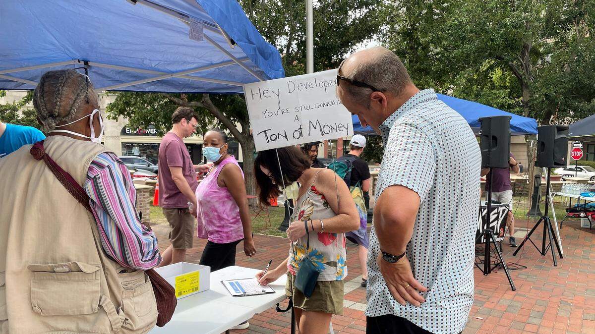 Supporters sign a petition asking city leaders to ensure 30% of future housing is priced at a rate affordable to lower-income families during a break in the Thirty for Thirty rally Saturday, Aug. 20, 2002, on the CCB Plaza in downtown Durham.