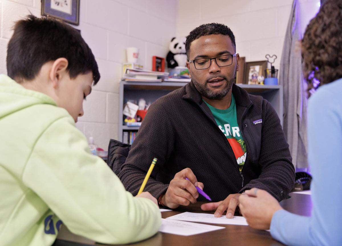 Shane Henderson, who attend grade school and high school in Chatham County, works with Jimmy Keck, left, and another student at Pittsboro Elementary School. 