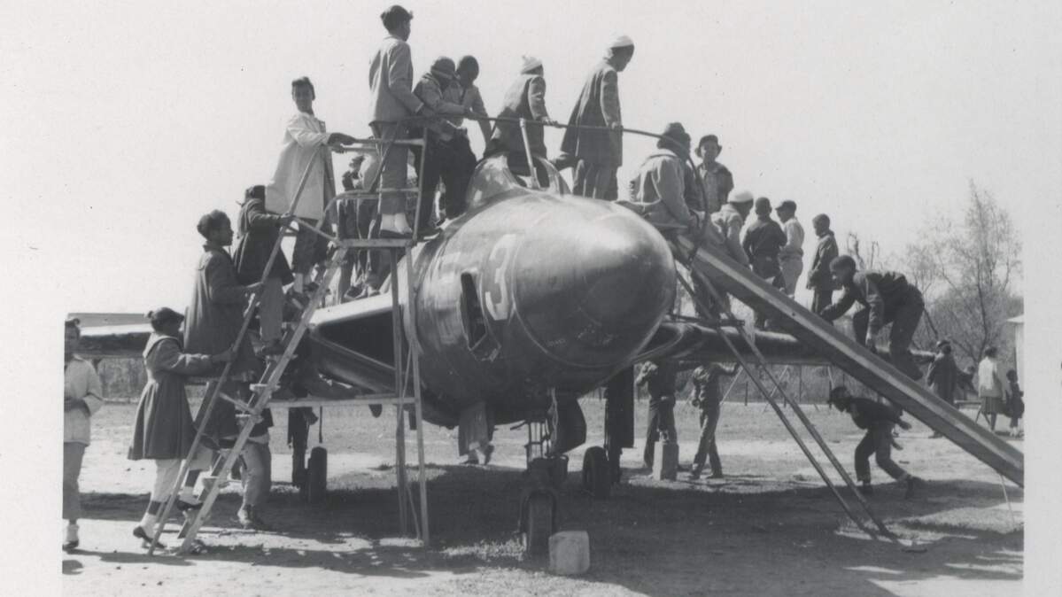 This photo shows children playing on the airplane at John Chavis Memorial Park in East Raleigh. The Korean War-era F9F-6 Cougar Marine Corps jet was added to the park as a play feature in 1960. Kids climbed up one side and slid down the other.