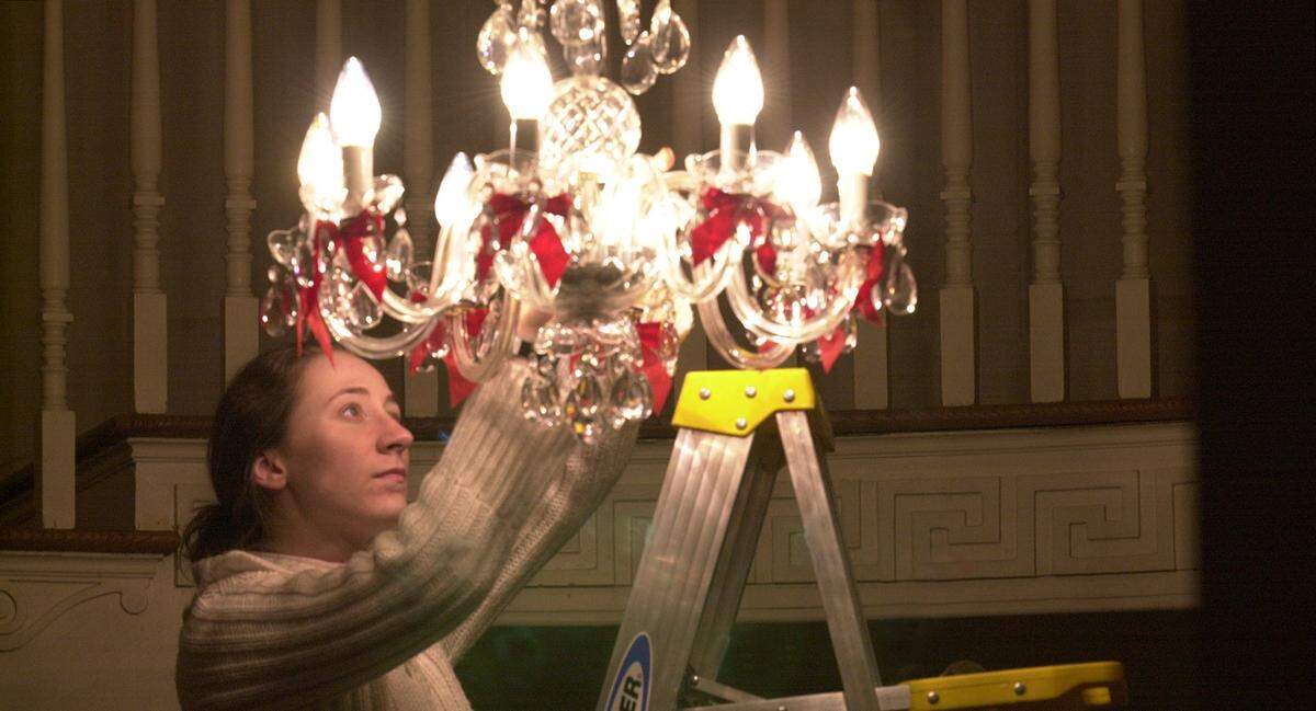 As the Peterson family tries to return to a sense of normalcy Michael Peterson’s adopted daughter, Margaret Ratliff replaces a burned out bulb in the foyer’s chandelier, Feb. 15, 2002.