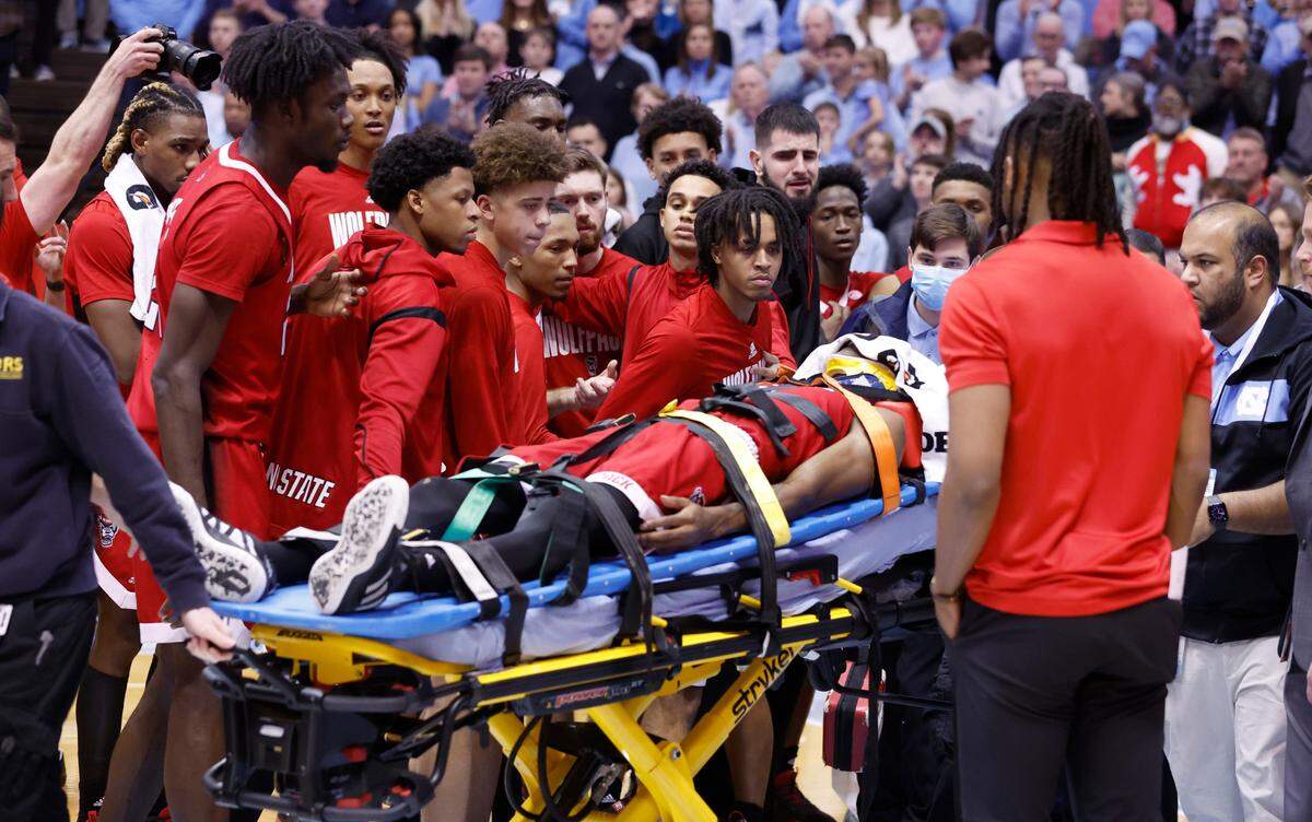 Wolfpack teammates watch as N.C. State’s Terquavion Smith is stretchered off the floor after being injured during the second half of N.C. State’s game against UNC at the Smith Center in Chapel Hill, N.C., Saturday, Jan. 21, 2023.