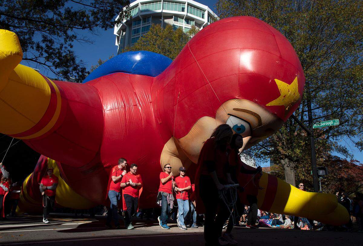 People guide a large balloon down Hillsborough Street during the Raleigh Christmas Parade on Saturday, Nov. 18, 2023.