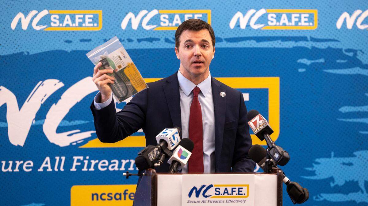 North Carolina Attorney General Jeff Jackson holds a gun lock during a news conference announcing the N.C. S.A.F.E. for Schools program, a statewide campaign to provide all 115 school districts with information to share with families about the safe storage of firearms, Thursday, April 24, 2025, at Garner Magnet High School.
