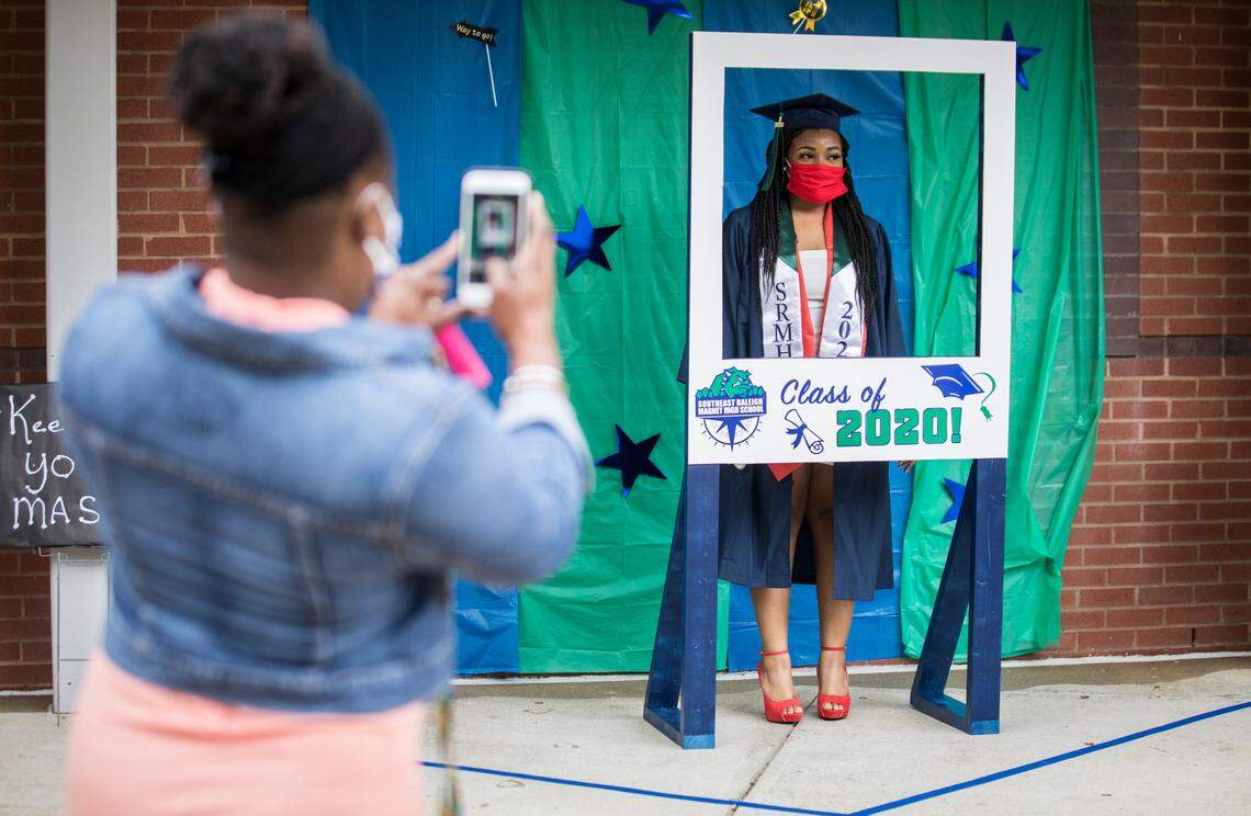 Jonty Constant, left, takes a picture of her daughter Nyla before she walked inside Southeast Raleigh High School’s auditorium to receive her diploma at the school’s socially distanced graduation ceremony on Wednesday, May 27, 2020.