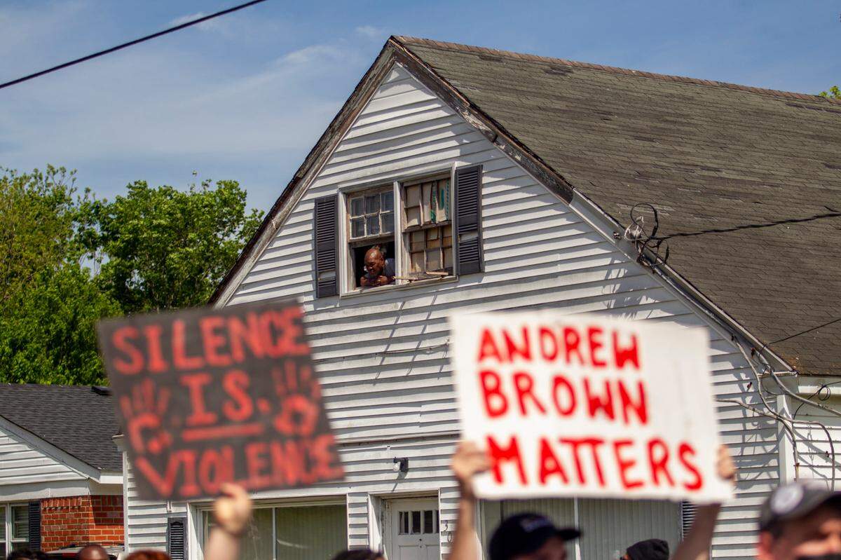 A man watches from an upstairs window as hundreds of demonstrators led by Andrew Brown Jr.’s family and Rev. Greg Drumwright Sunday, May 2, 2021 to the site where Brown was shot and killed by Pasquotank County Sheriff deputies. Brown’s funeral will be held Monday.
