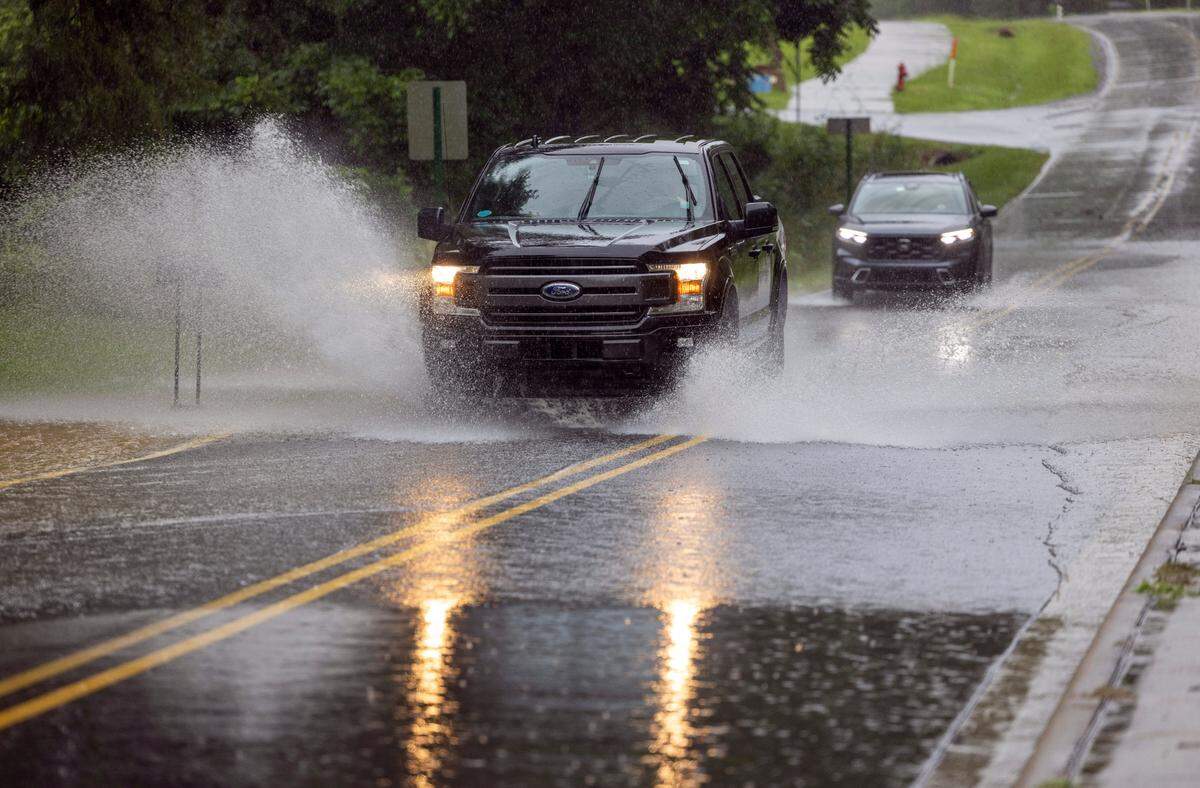 Vehicles traverse Thompson Street in Pittsboro, N.C. Drivers are urged not to drive through floodwaters or around barriers.