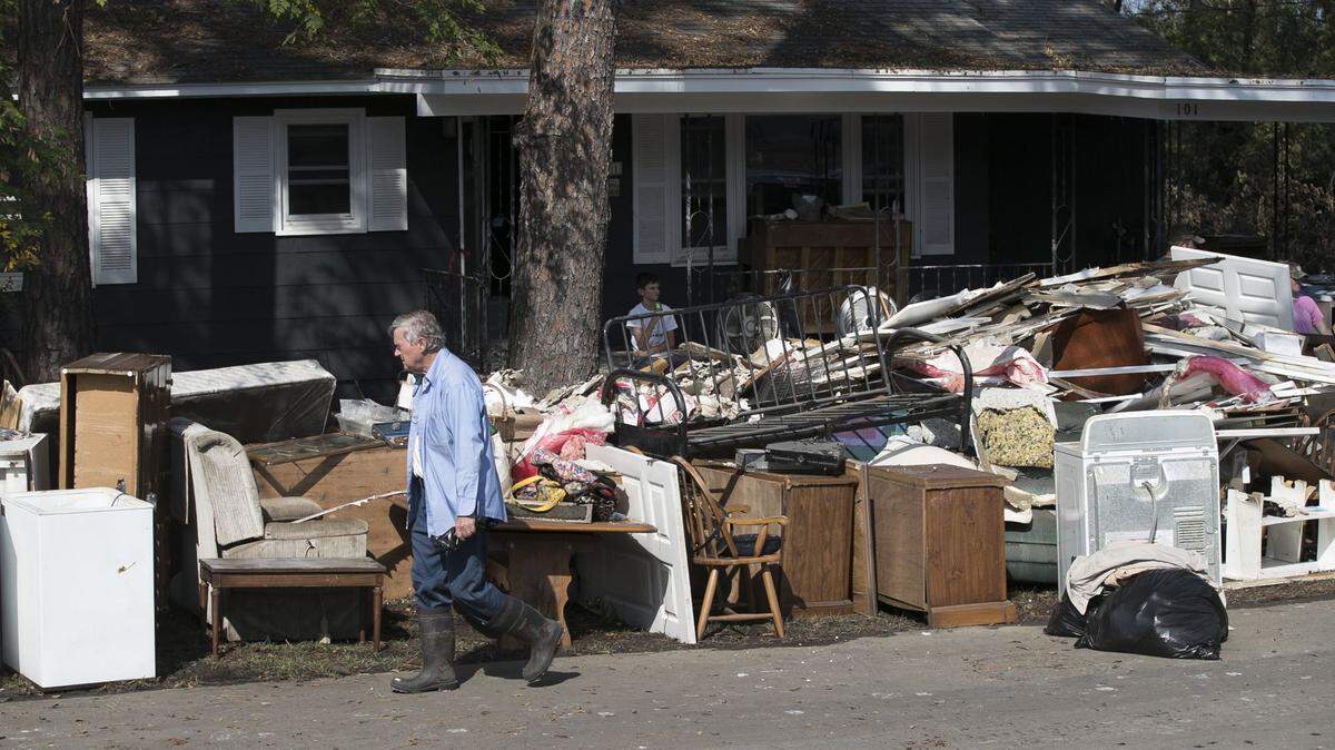 In this Sept. 2018 file photo Bob Adams walks past the discarded belonging of his mother’s home in Trenton, N.C. The home located next to the Trent River had more than five feet of water in the kitchen at the height of flooding from Hurricane Florence. Adams’ mother Bertha Adams evacuated to Elizabeth City during the storm.