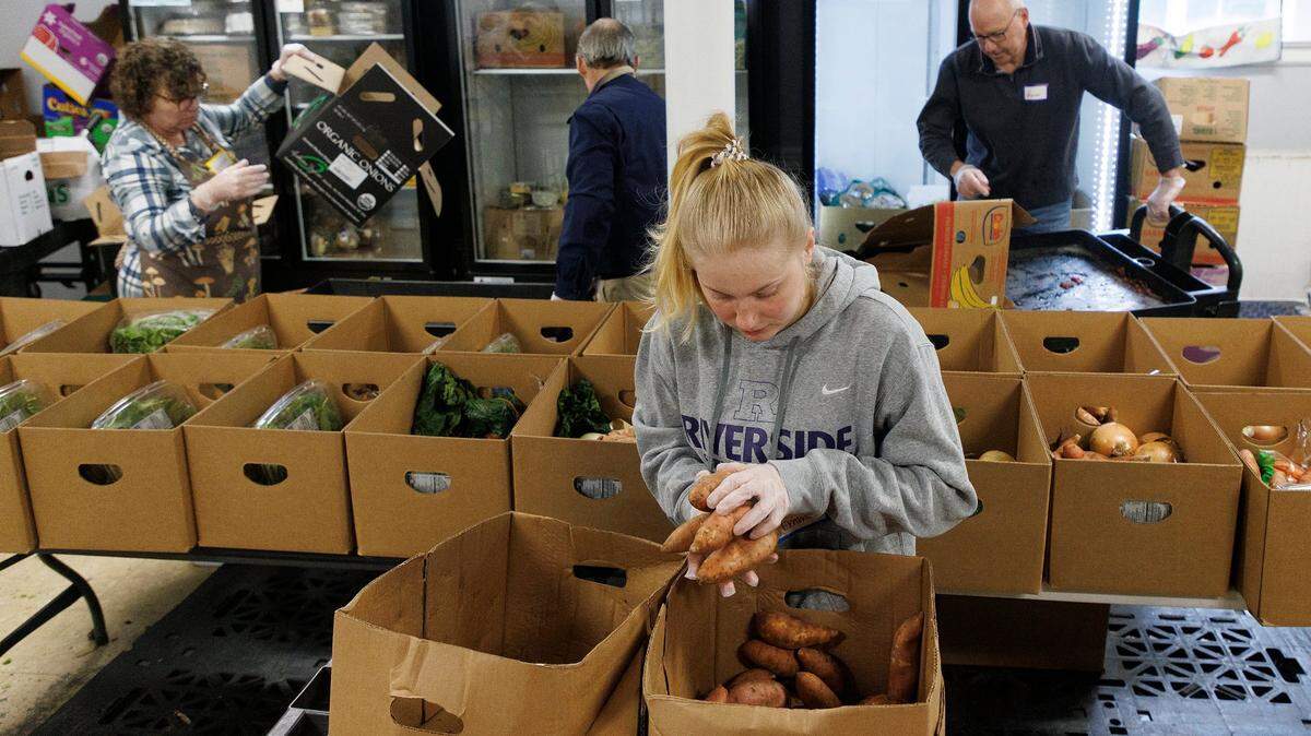 Emma Wilcox, a senior at Riverside High School, adds sweet potatoes to boxes of fresh produce for distribution at a weekly food pantry at Iglesia Presbiteriania Emanuel on Wednesday, Jan. 31, 2024, in. Durham, N.C.