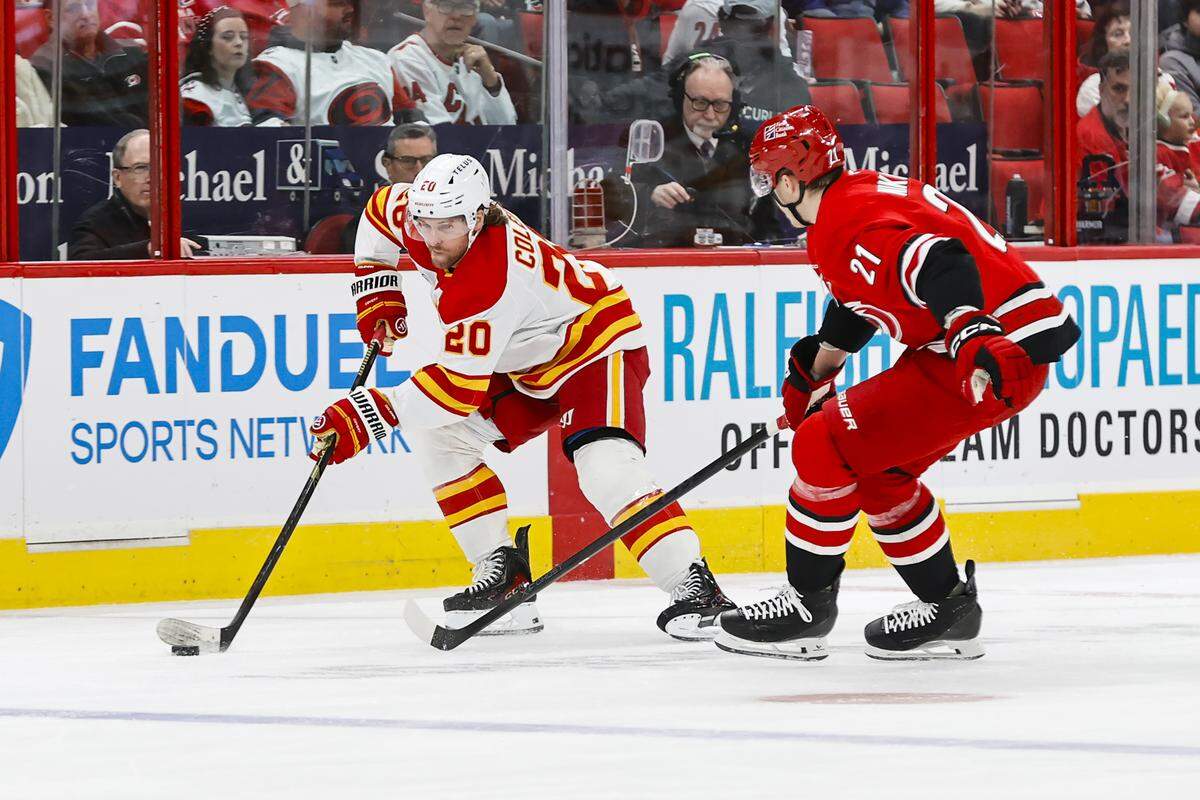 Blake Coleman (20) of the Calgary Flames skates with the puck guarded by Alexander Nikishin of the Carolina Hurricanes during the first period at Lenovo Center on Nov. 30, 2025 in Raleigh, North Carolina.