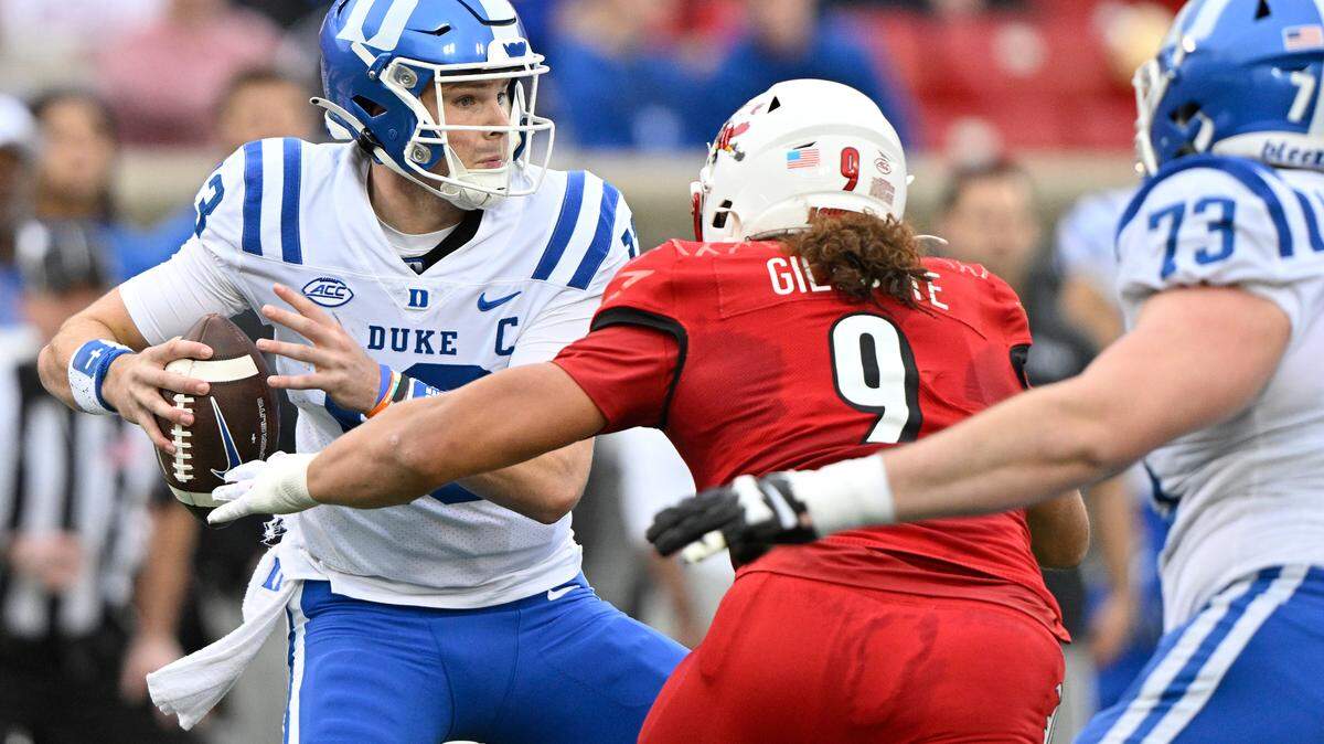 Duke Blue Devils quarterback Riley Leonard (13) tries to avoid a sack by Louisville Cardinals defensive lineman Ashton Gillotte (9) during the second quarter at L&N Federal Credit Union Stadium.