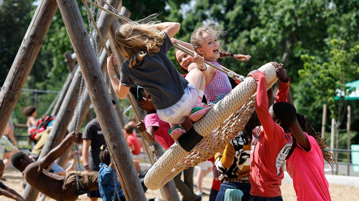 Nova Price, 11, of Raleigh, center, is one of the many enjoying the 91-foot long mega swing at Gipson Play Plaza at Dix Park in May.