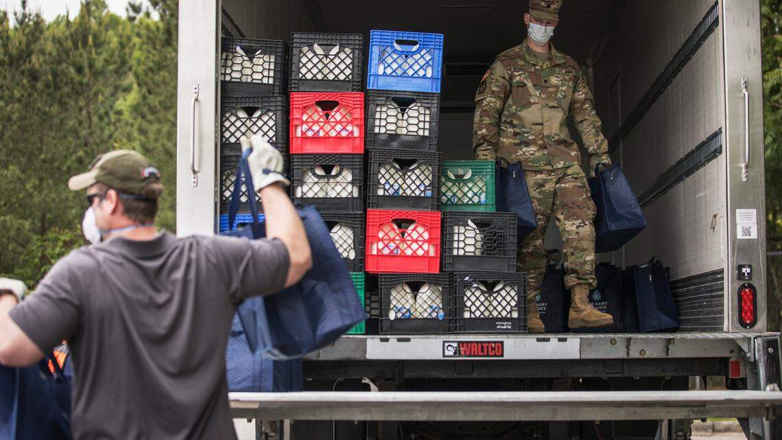 Sam Levinson, left, moves bags of dairy products donated by Maple View Farms, as Army National Guard Specialist Jacob Wahmhoff unloads more bags outside Cedar Ridge High School in Hillsborough, N.C. on Wednesday, May 13, 2020. The Food Bank of Central and Eastern North Carolina partnered with the Gary Sinise Foundation to donate over 300 boxes of food to veterans, active duty military members and their spouses.