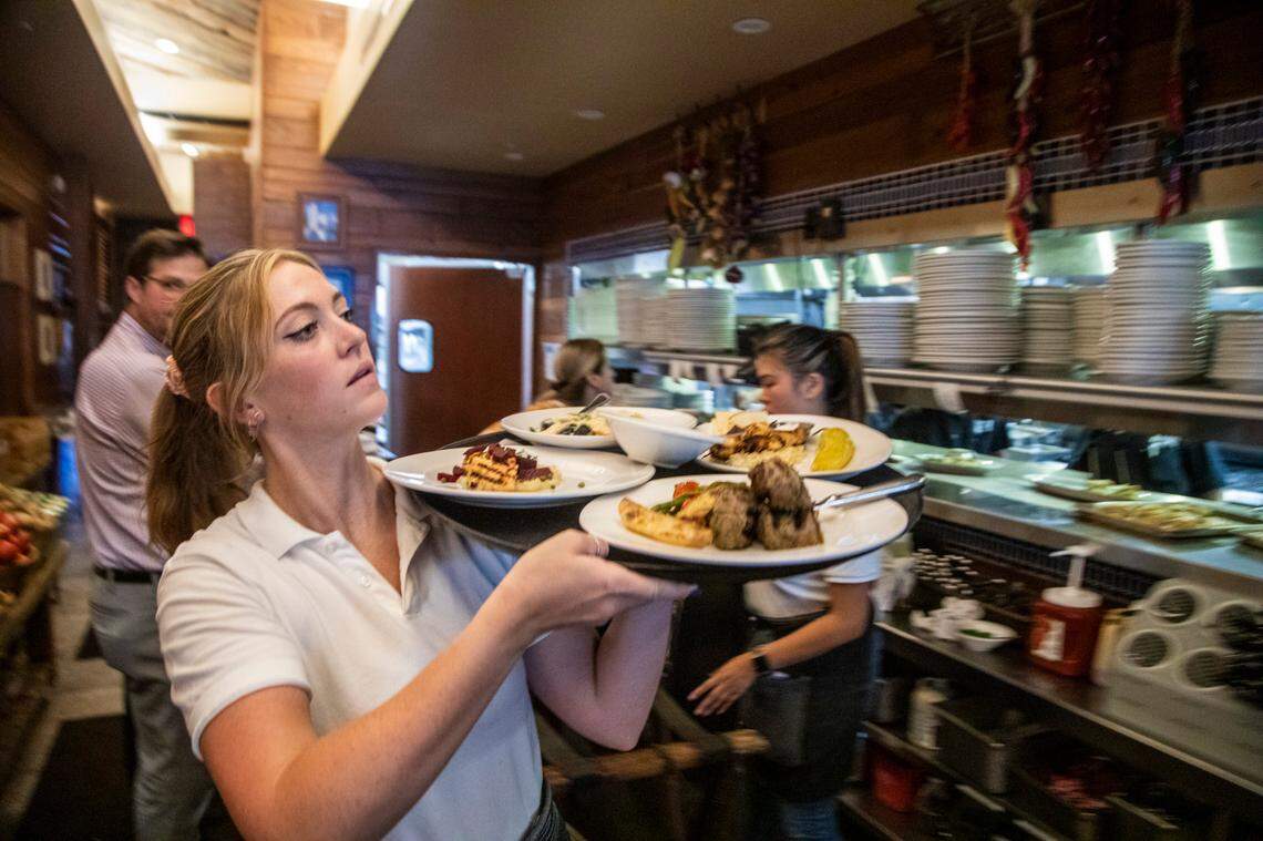 Server Charlotte Jones takes food to diners Wednesday, June 16, 2021 at Taverna Agora Greek Kitchen & Bar in Raleigh. Many restaurants say business is starting to return to normal as coronavirus restrictions have lifted but hiring remains a challenge.