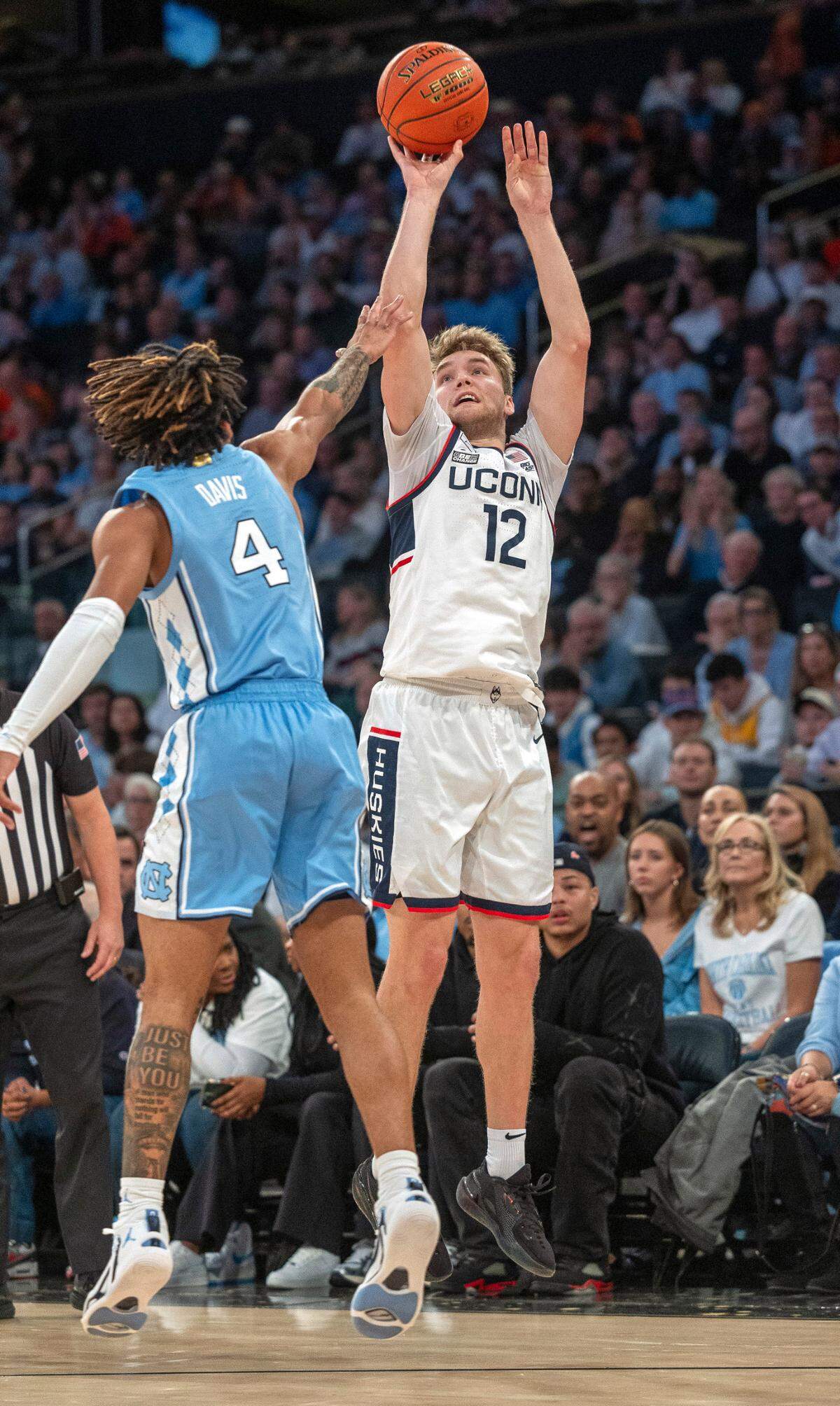 Connecticut’s Cam Spencer (12) launches a three-point shot over North Carolina’s R.J. Davis (4) in the first half during the first half in the Jimmy V Classic on Tuesday, December 5, 2023 at Madison Square Garden in New York, NY. Spencer lead UConn with 23 points.