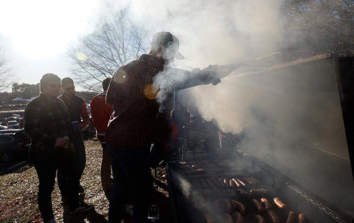 Josh Lamb checks on the burgers, brats and dogs while tailgating before the NHL Stadium Series game between the Carolina Hurricanes and the Washington Capitals at Carter-Finley Stadium in Raleigh, N.C., Saturday, Feb. 18, 2023.