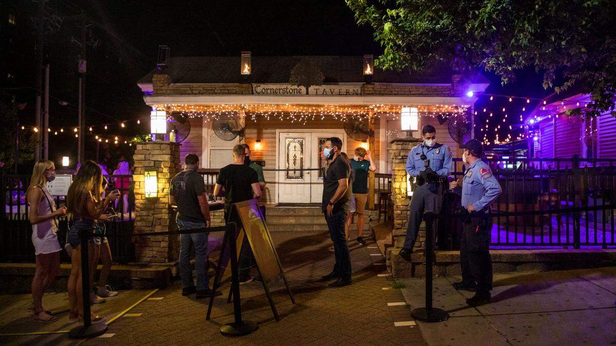 Two Raleigh police officers stand outside the Cornerstone Tavern on Glenwood Avenue, which opened its doors for business despite Gov. Roy CooperÕs veto of legislation to reopen bars and a judgeÕs decision hours earlier denying a lawsuit brought against the governorÕs executive orders by the N.C. Bar and Tavern Association, on Friday, Jun. 26, 2020, in Raleigh, N.C.