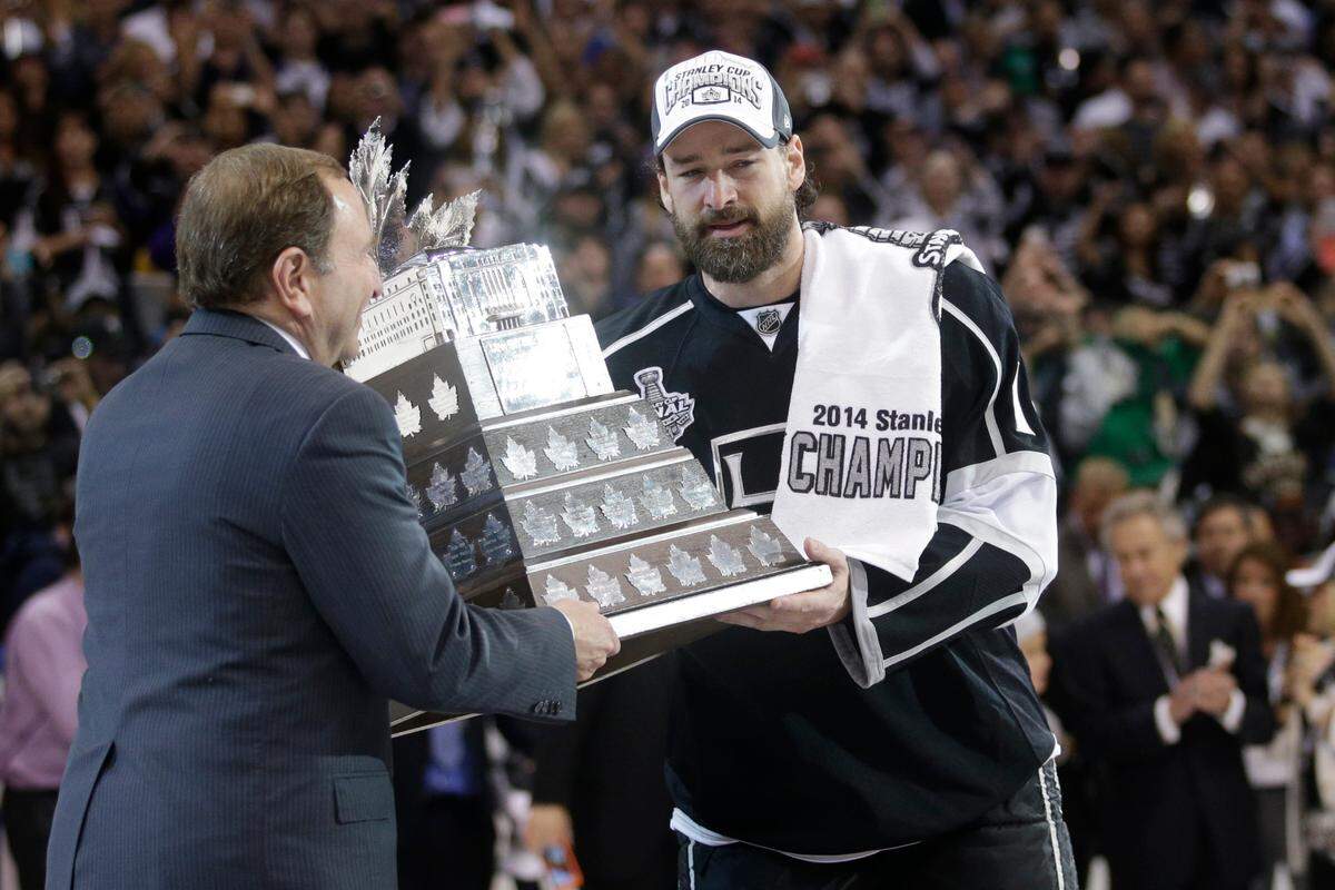 Los Angeles Kings right wing Justin Williams, right, is handed the Conn Smythe Trophy by NHL commissioner Gary Bettman, left, after the Kings beat the Rangers in Game 5 of the NHL Stanley Cup Final series Friday, June 13, 2014, in Los Angeles. (AP Photo/Jae C. Hong)